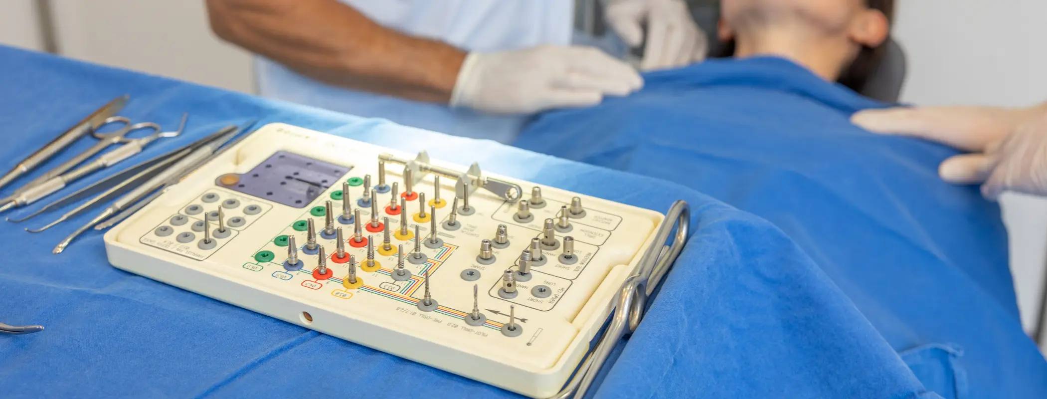 Operationswerkzeug mit Patienten im Hintergrund | Gemeinschaftspraxis Dr. Dr. Jürgen Wahn - Dr. Dr. Tassilo Illg